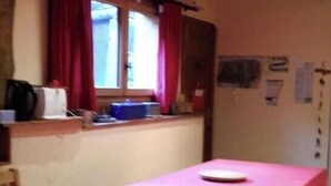 Ein Zimmer mit einem Bett, einem Sessel, einem Tisch und einem fensterbepflanzten Fenster.