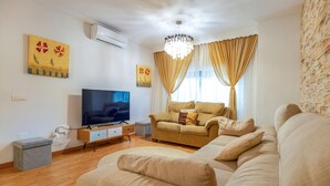 Una sala de estar con televisor, sofá y cortinas.