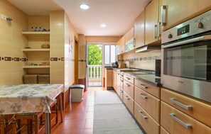 A modern kitchen with wooden cabinets, stainless steel appliances, and a dining area with a table and chairs. - Nice apartment in Fuengirola with WiFi (Fuengirola)
