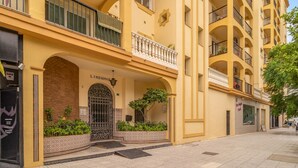 Un edificio amarillo de varios pisos con balcones, una reja de hierro forjado y un letrero que dice "LINDAMAR".