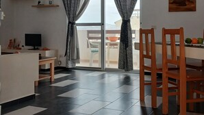 Cocina moderna con comedor, televisor y balcón con vistas.