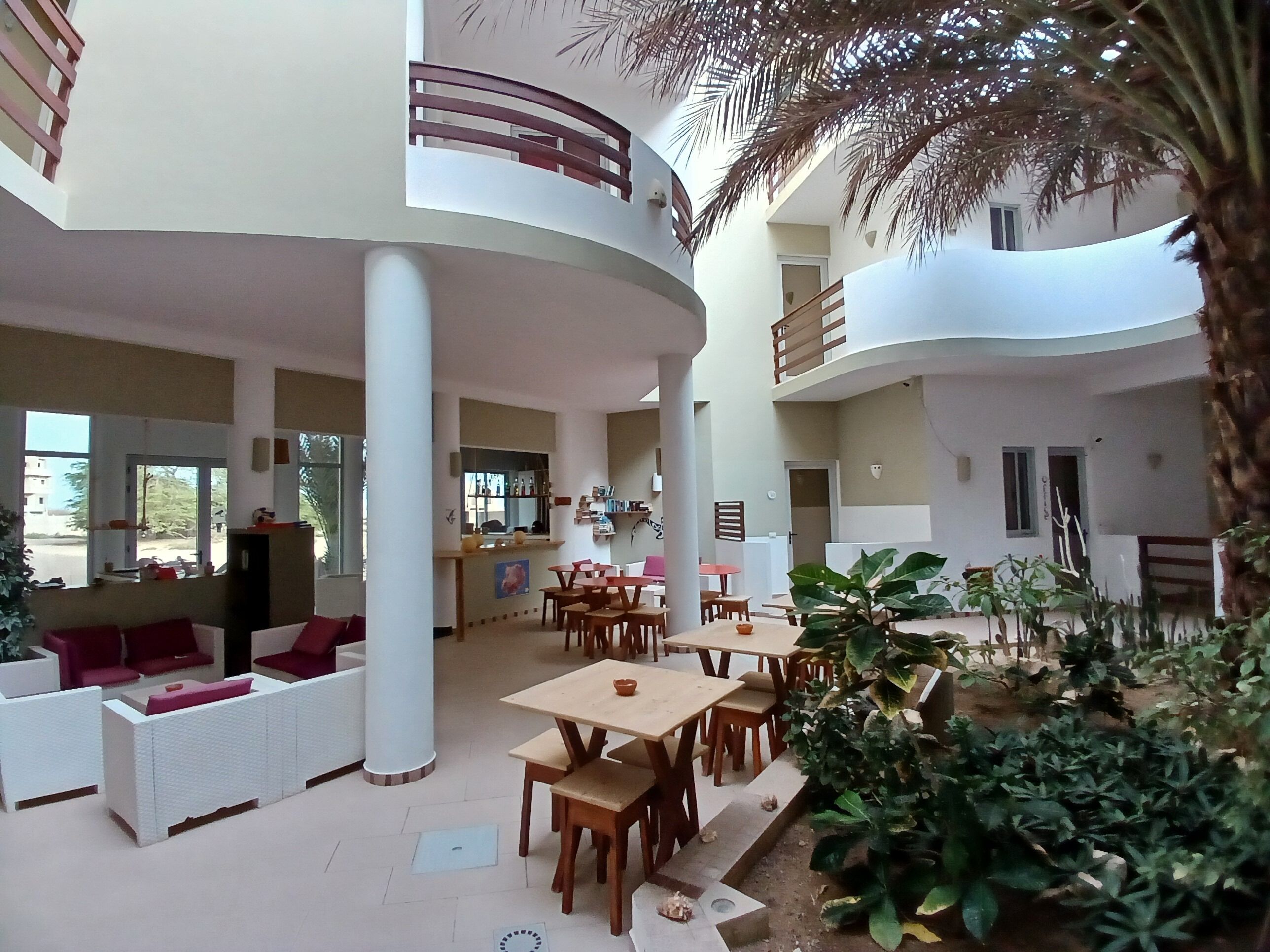 Un vaste espace intérieur aménagé avec différents types de sièges, notamment des canapés et des tables, et une colonne centrale.