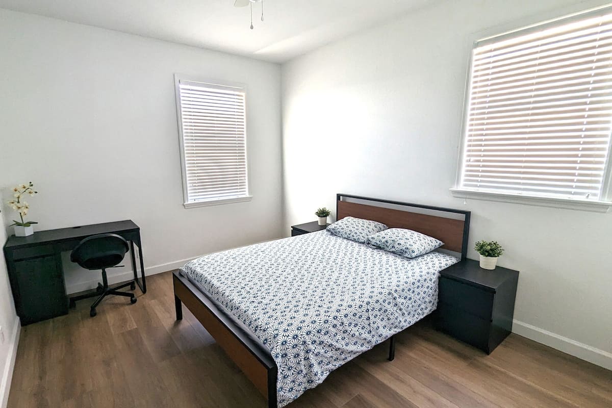 Un dormitorio con una cama, un escritorio y dos mesitas de noche.