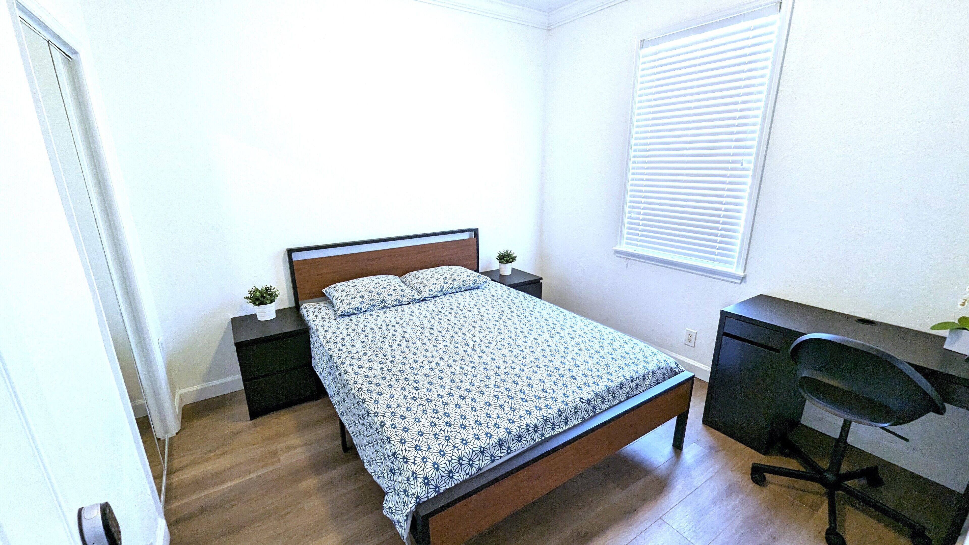 Een slaapkamer met een bed, een bureau en een stoel.