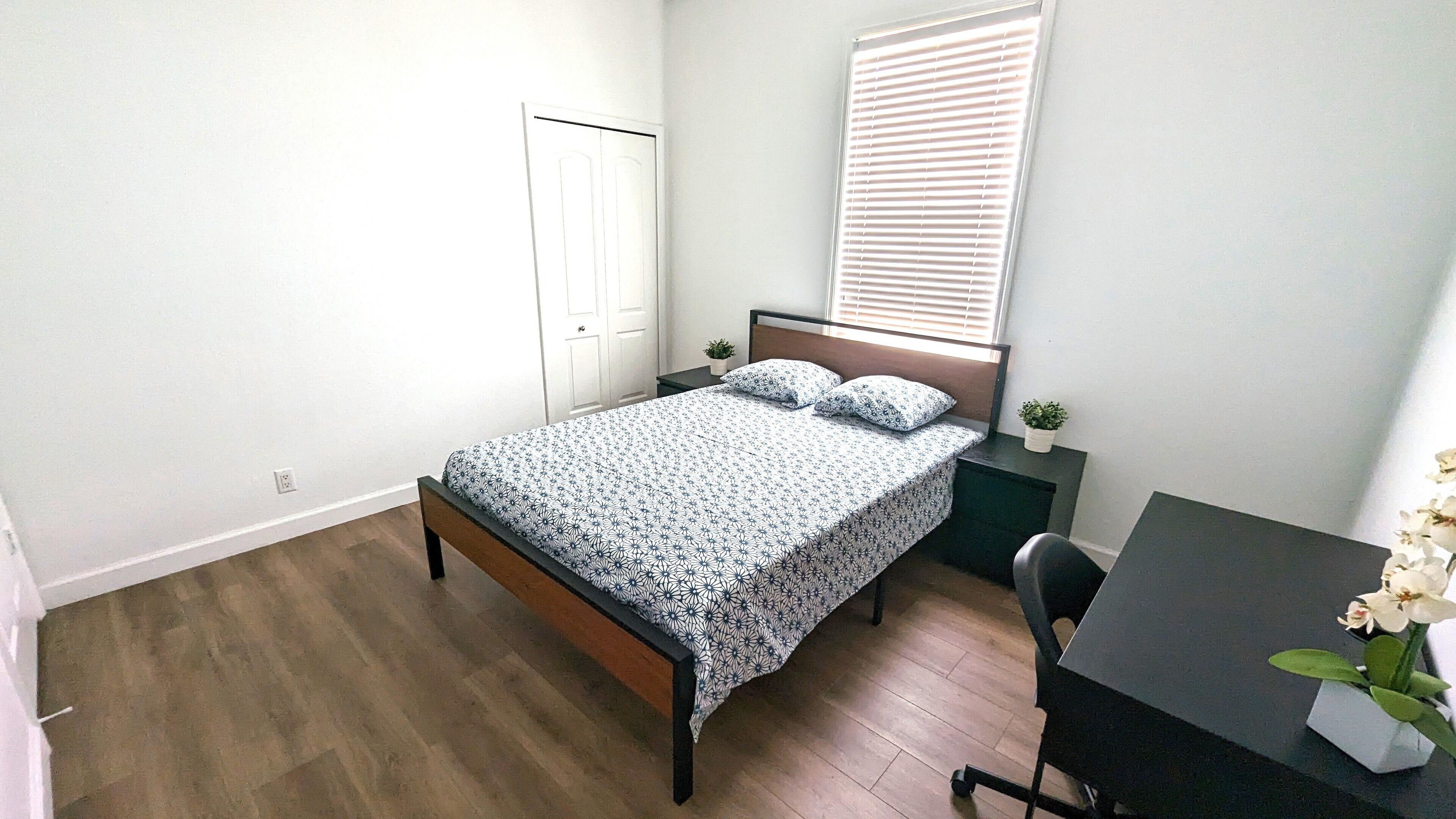 Een slaapkamer met een bed, een bureau en een stoel.