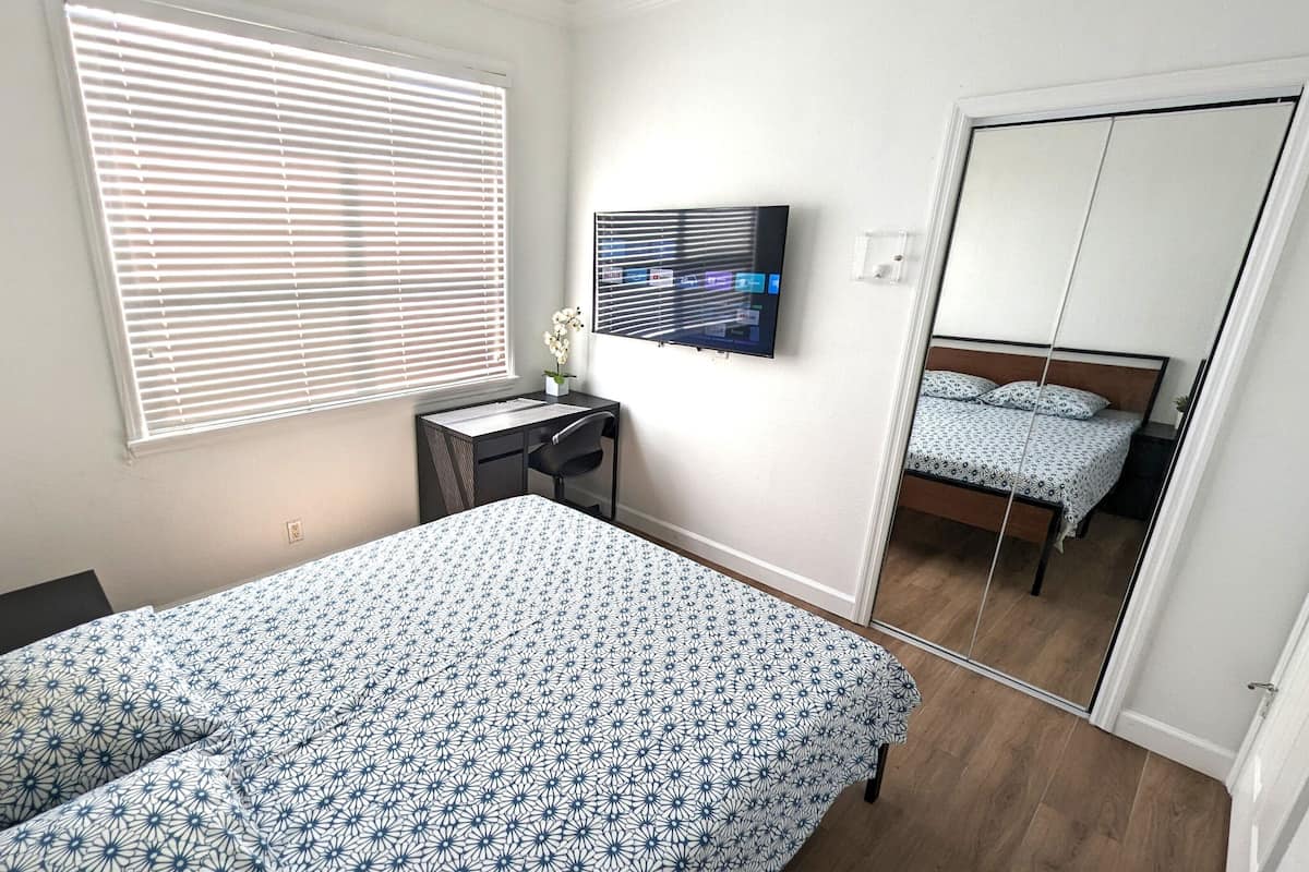 Un dormitorio con cama, un escritorio con silla, televisor y armario.