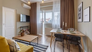 A modern living room with a yellow sofa, a wooden coffee table, and a dining area with a table set for four.