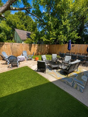 A backyard with a wooden fence, outdoor furniture, and a grassy area.