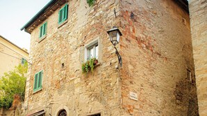 Un edificio de piedra con puerta y ventanas de madera, una farola y un cartel que dice "VIA RAFFAELLA".