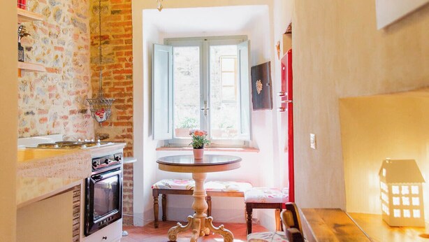 Una cocina acogedora con paredes de ladrillo visto, techo de madera y una araña.