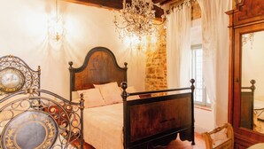 Un dormitorio con una cama de madera, una pared de piedra, una araña y un espejo.