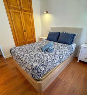A bedroom with a bed, nightstands, a wardrobe, and a wall-mounted light.