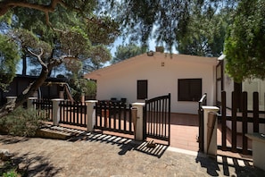 Uma casa com entrada protegida por portão, caminho de pedra e área de pátio.