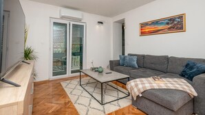 A living room with a grey sofa, a coffee table, and a painting on the wall. - Amazing home in Prolozac Donji (Prolozac Donji)