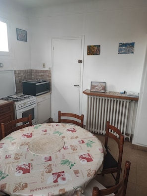 A compact kitchen with a dining table, chairs, a stove, and a radiator. - Detached house (Franconville)