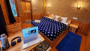 Una habitación con paneles de madera, una cama, un ordenador portátil y una ventana con cortinas.