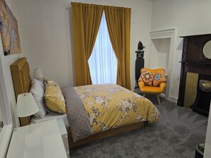 A bedroom with a bed, a chair, a lamp, and a fireplace. - The Boot & Shoe (Darlington)