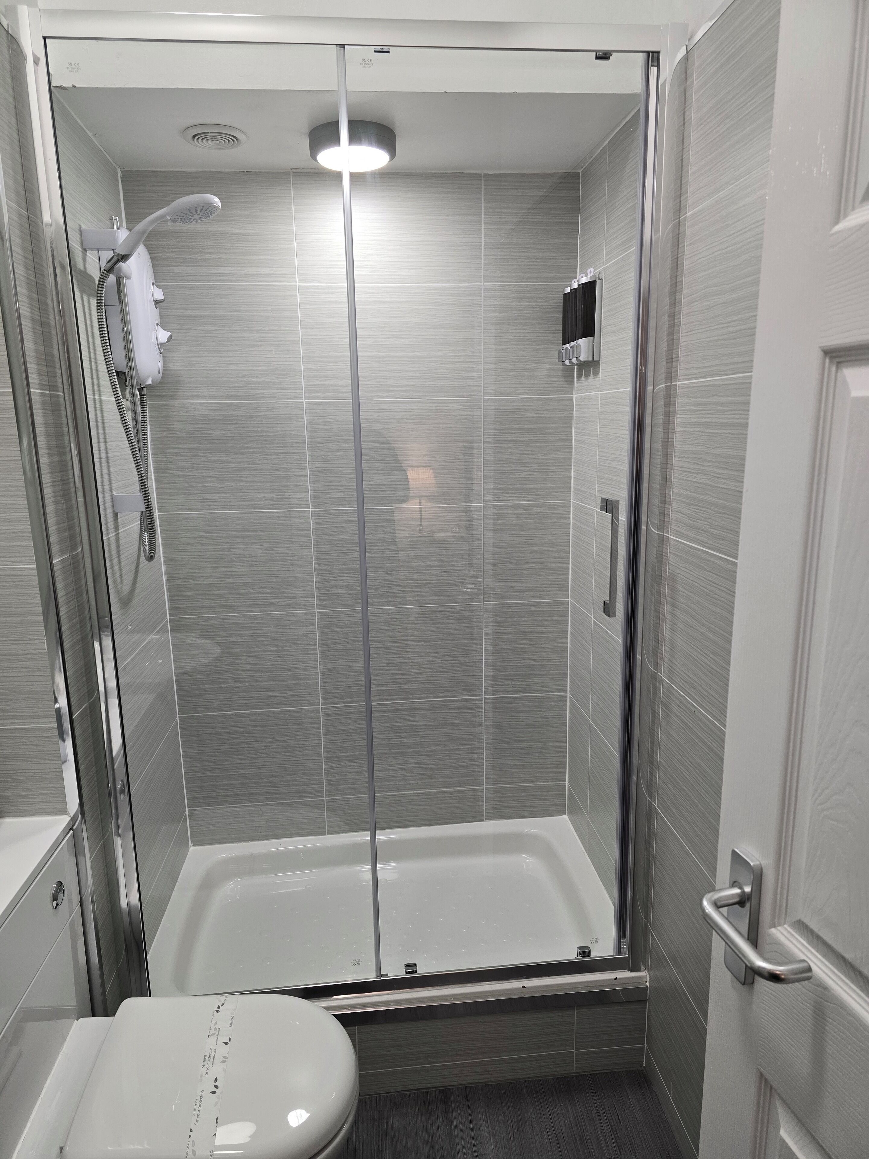 Un baño moderno con ducha acristalada, inodoro y lavabo.