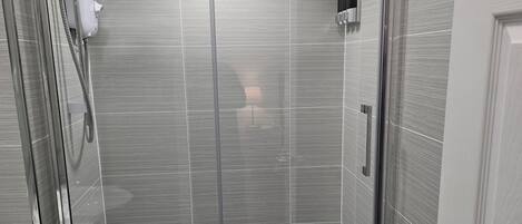 Un baño moderno con ducha acristalada, inodoro y lavabo.