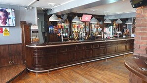 A bar area with a wooden counter, multiple beer taps, and a variety of bottles and glasses. - The Boot & Shoe (Darlington)