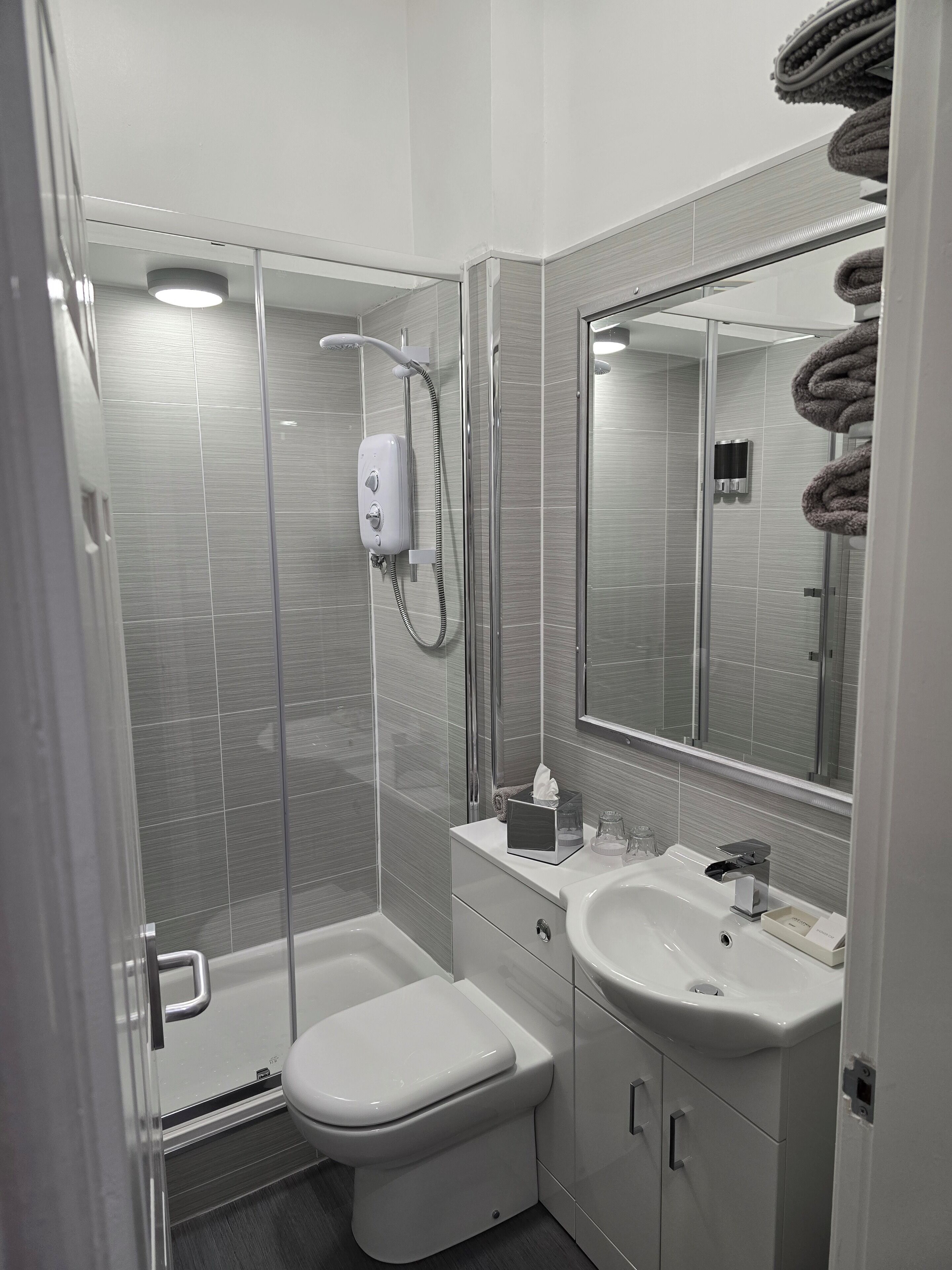 Un baño moderno con cabina de ducha de vidrio, inodoro, lavabo y espejo.