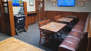 A restaurant with wooden furniture, a blue screen displaying games, and a sign encouraging social media engagement. - The Boot & Shoe (Darlington)