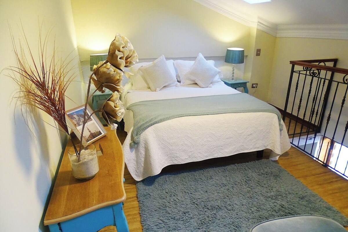 A bedroom with a bed, bedside table, lamp, and a view of a balcony.