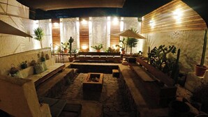 An outdoor patio area with stone flooring, wooden benches, and potted plants. - Terra Diaguita Hotel Boutique & Spa (La Serena)