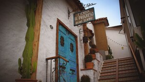 A building with a blue door, a sign above the door, and a staircase leading up to the entrance. - Terra Diaguita Hotel Boutique & Spa (La Serena)