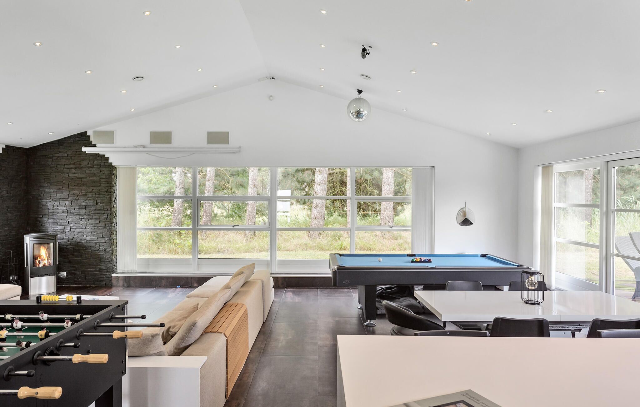 Una sala de estar moderna con una mesa de fútbol de mesa, una mesa de billar y una chimenea de piedra.