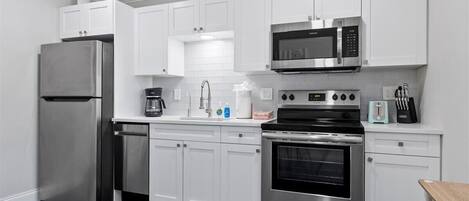 A modern kitchen with white cabinets, stainless steel appliances, and a blue floor.