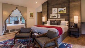 Una camera da letto con un letto, due poltrone, un angolo per la lettura e un'ampia finestra.