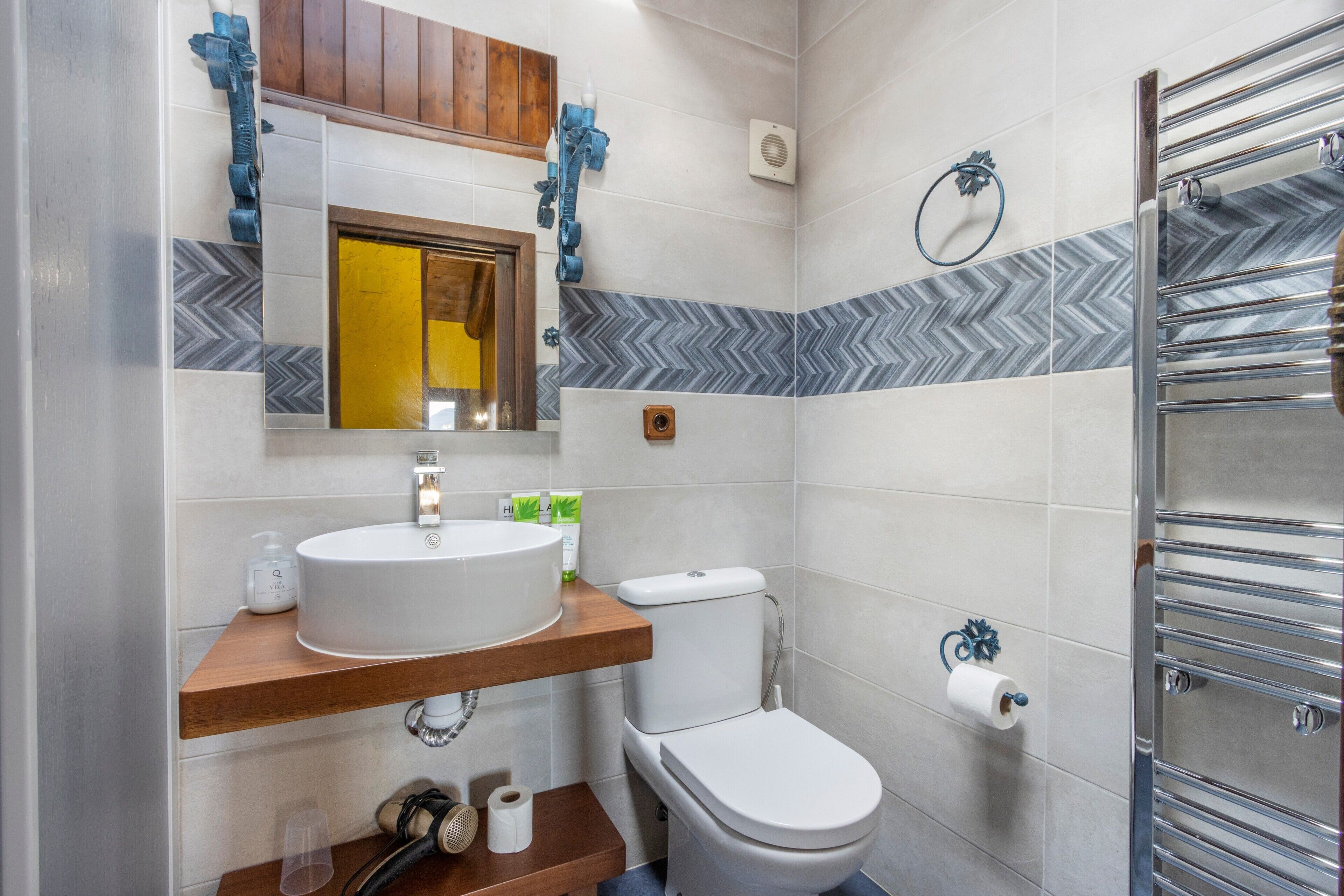 Un baño con lavamanos blanco, inodoro y barra para toallas.