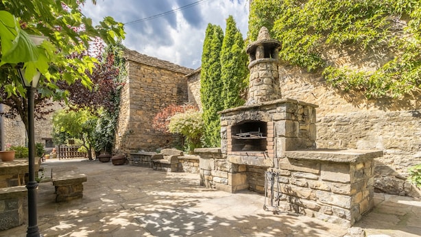 A stone courtyard with a traditional brick oven, stone benches, and potted plants. - Apartment 'Bachella' with Mountain View, Private Terrace and Wi-Fi (Borrastre)