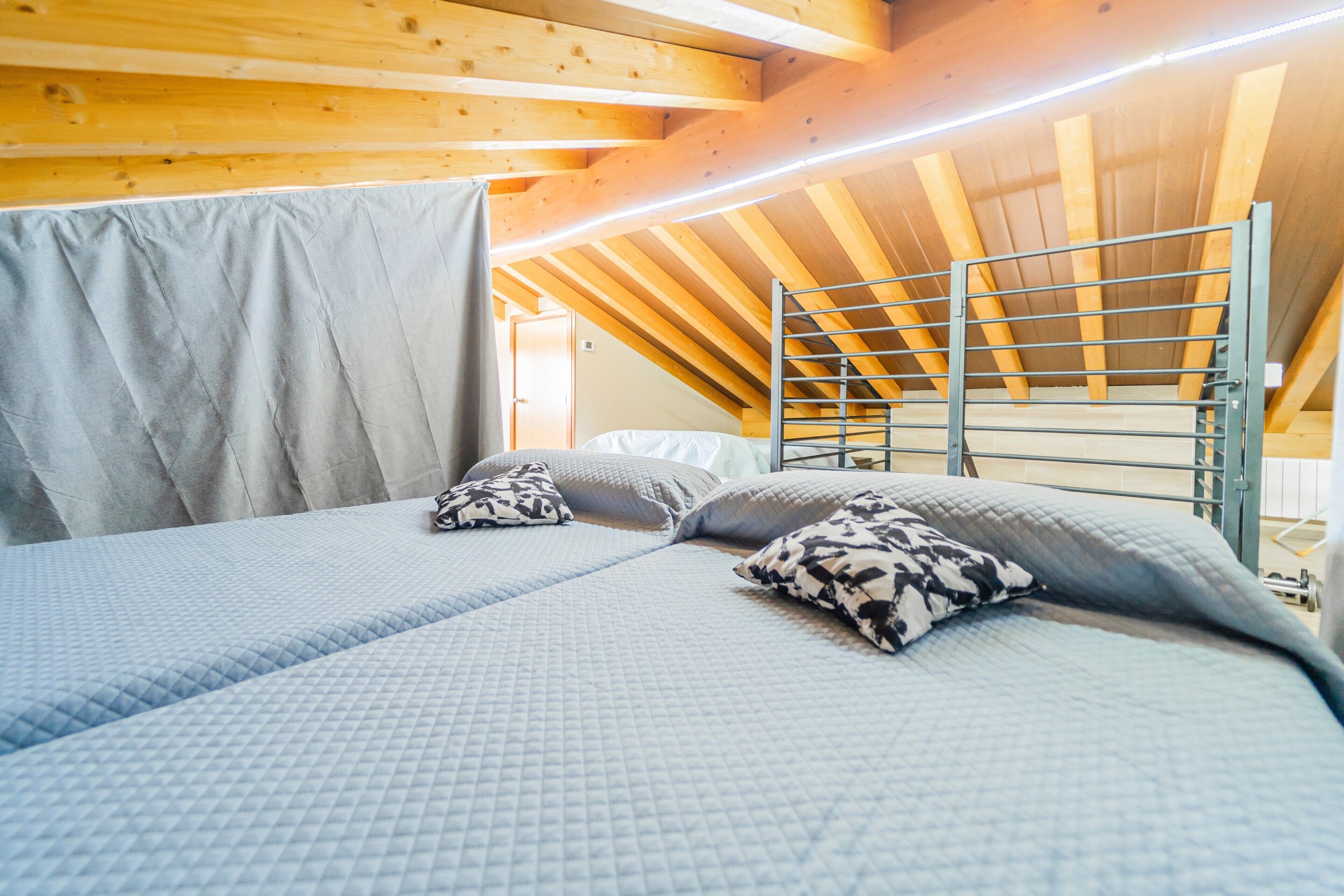 A room with a bunk bed, a ladder, and a wooden ceiling.