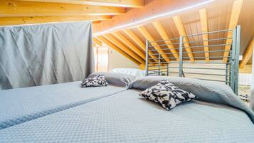 A room with a bunk bed, a ladder, and a wooden ceiling.