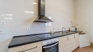 Eine Küche mit schwarzem Arbeitsplatz, weißen Schränken, einer Edelstahl-Dunstabzugshaube, einer Mikrowelle und einem Spülbecken.