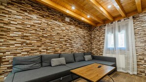 Ein Zimmer mit Holzboden, einer Ziegelwand, einem grauen Sofa und einem Holztisch.