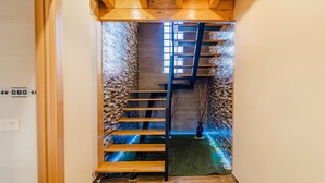 Eine Holztreppe mit schwarzer Handlauf, die zu einer höheren Etage führt.