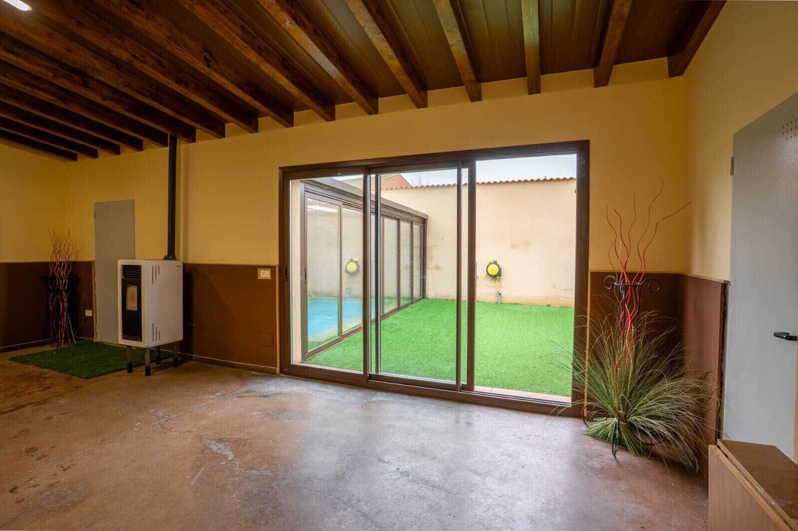 Habitació amb sòl de formigó, una porta corredissa de vidre que dona a un pràt verd i un sostre de fusta.