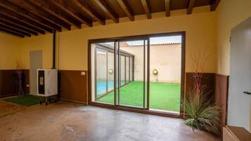 Habitació amb sòl de formigó, una porta corredissa de vidre que dona a un pràt verd i un sostre de fusta.