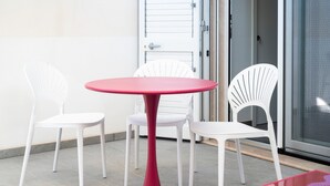 Un petit espace extérieur aménagé avec une table ronde et quatre chaises blanches.