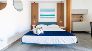 Une chambre d’hôtel moderne, équipée d’un lit, d’un bureau et d’un tableau représentant une plage.