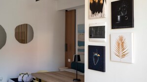 Une chambre moderne avec une table en bois, une lampe et des œuvres d’art murales, notamment une plume et une tasse.