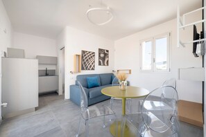 A modern living space with a sofa, a round table, and clear chairs.