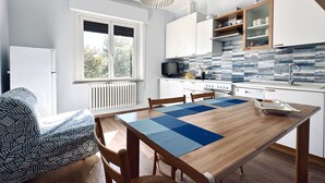 A modern kitchen with white cabinets, a tiled backsplash, and a dining area with a wooden table and chairs. - S341 - Sirolo, new two-room apartment in the center with parking space (Sirolo)