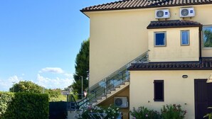 A two-story building with a tiled roof, a staircase, and potted plants. - S341 - Sirolo, new two-room apartment in the center with parking space (Sirolo)