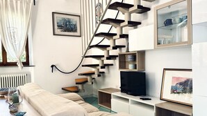 Ein modernes Wohnzimmer mit einer außergewöhnlichen Treppe, einer Couch, einem Fernseher und einem Essbereich.