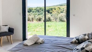 Ein Schlafzimmer mit einem großen Fenster, das einen Blick auf eine grüne Landschaft bietet.