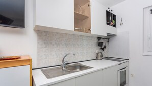 Eine moderne Küche mit weißen Schränken, einer Edelstahl-Spüle und einem eingebauten Backofen.